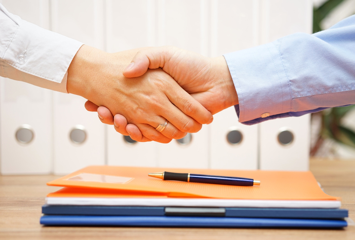 business man and woman are handshaking over documents
